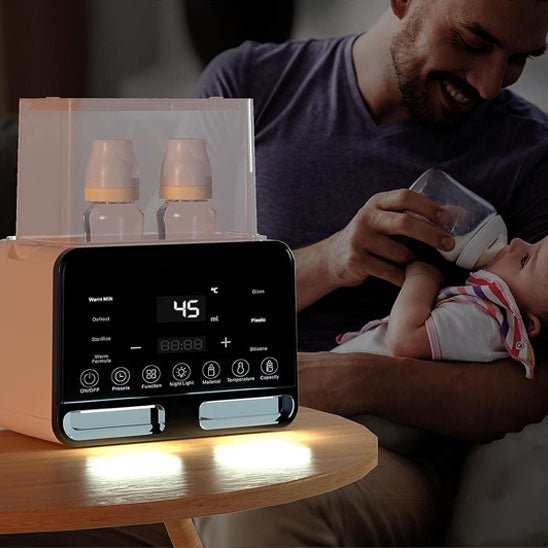 Papa donnant un biberon à son bébé avec un chauffe biberon à écran LED posé sur une table.