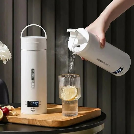Chauffe-biberon nomade blanc versant de l’eau chaude dans un verre sur table en bois