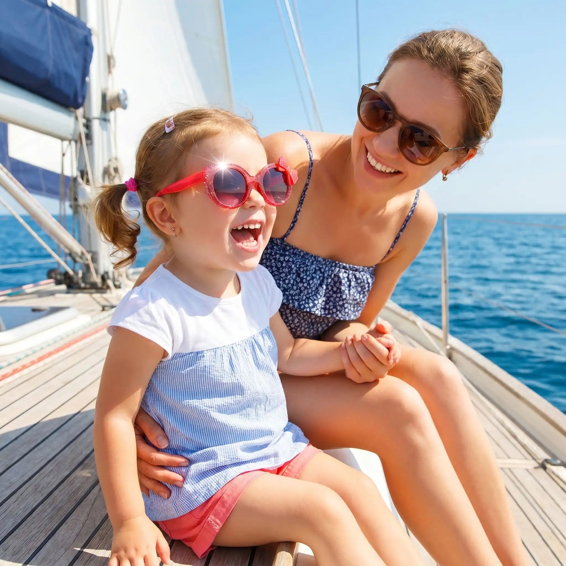 Petite fille portant des lunettes de soleil bébé rouges au design élégant lors d’une balade en bateau