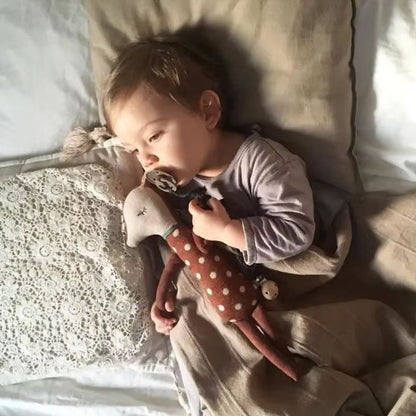 Bébé endormi câlinant un doudou biche marron, moment tendre et réconfortant