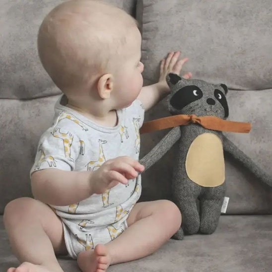 Bébé tenant un doudou raton laveur doux et rassurant pour accompagner 