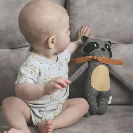 Bébé tenant un doudou raton laveur doux et rassurant pour accompagner 