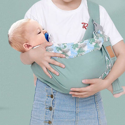 Écharpe de portage bébé verte avec motif feuillage, bébé endormi confortablement dans les bras de maman
