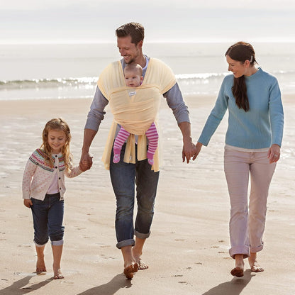 Famille se promenant sur la plage avec bébé porté en echarpe sling ergonomique