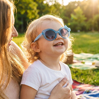 Bébé portant des lunettes de soleil bébé rouges avec nœud décoratif élégant pendant une balade à la plage