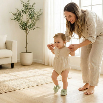 Maman aidant sa princesse à marcher avec une chaussure bebe fille verte