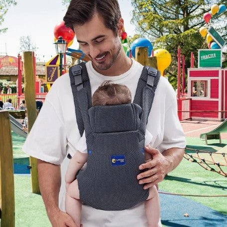 Papa portant son bébé en porte-bébé ergonomique lors d’une promenade au parc