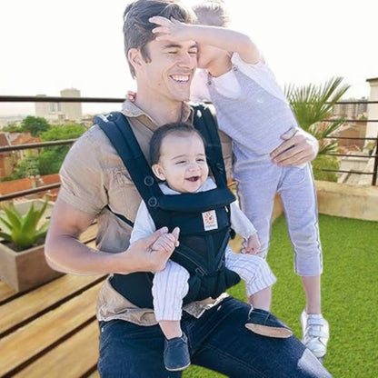 Papa portant son bébé avec porte bebe noir dans un jardin, moment de portage confortable et sécurisé