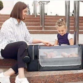 Bébé allonge dans un sac à dos à langer entoure par sa maman et sa grande sœur