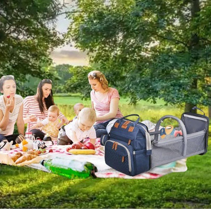 Sac a dos a langer ouvert lors d’un pique-nique entre mamans avec leurs bebes dans un parc