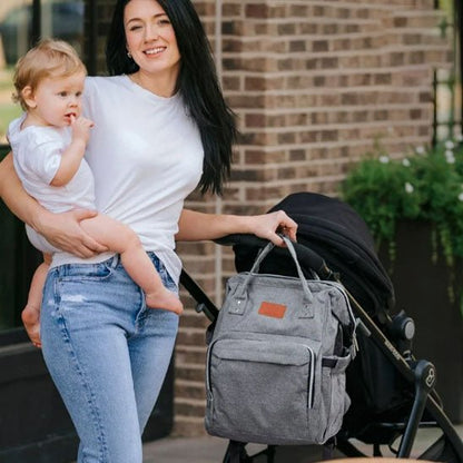Maman avec bébé et sac à langer gris accroché à la poussette