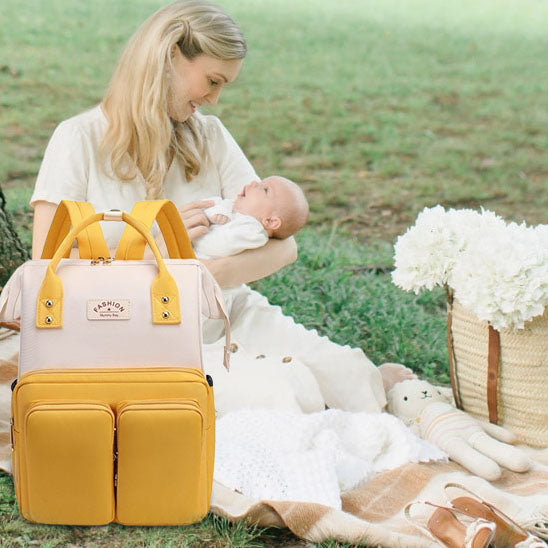Maman avec son bébé au parc portant sac a langer jaune pratique et tendance