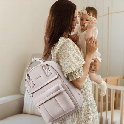 Maman portant son bébé et un sac à langer sac à dos gris élégant sur le dos dans un intérieur chaleureux