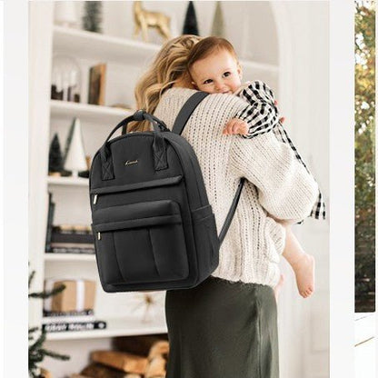Maman portant son bébé et un sac à langer sac à dos noir élégant sur le dos dans un intérieur chaleureux